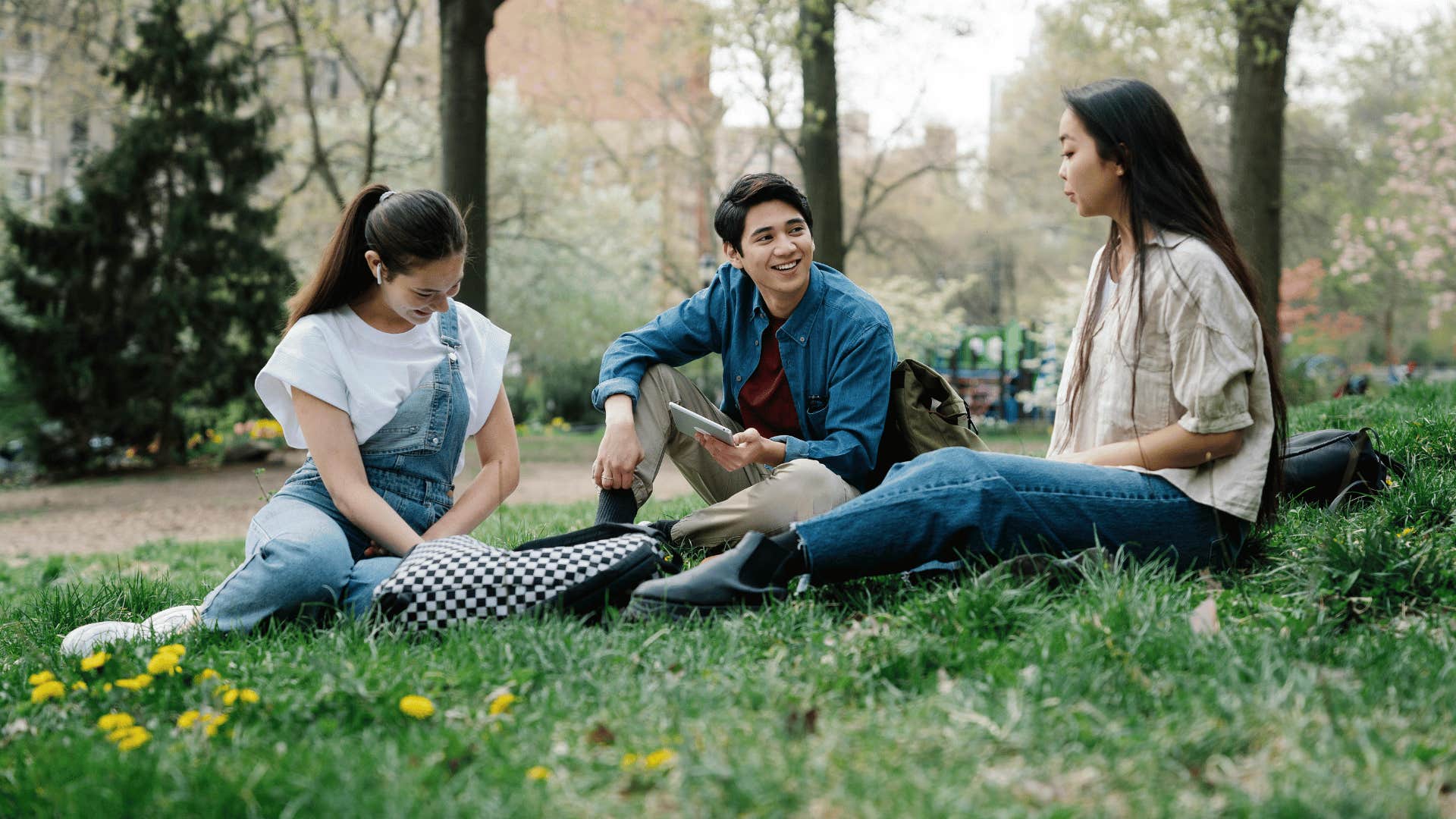 man sitting on grass with two friends