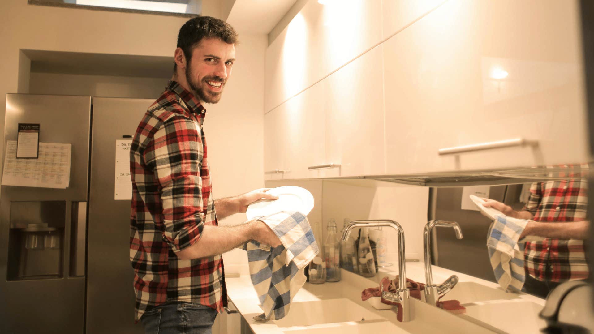 man washing dishes while smiling