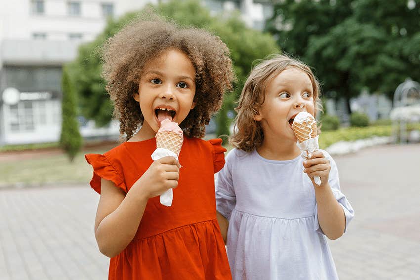 a two girl friends eats ice cream on a hot day.