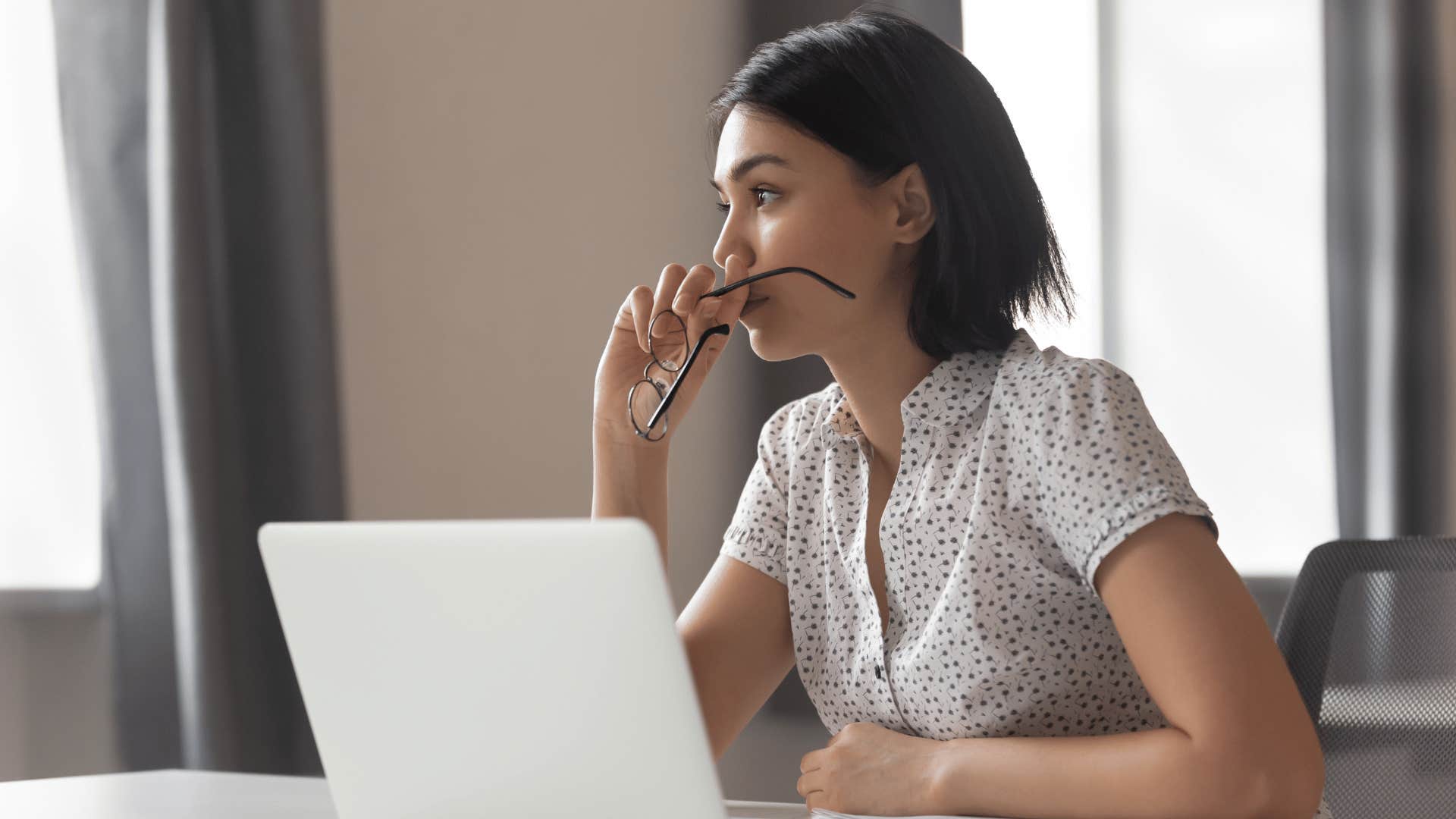 woman taking glasses off and thinking 