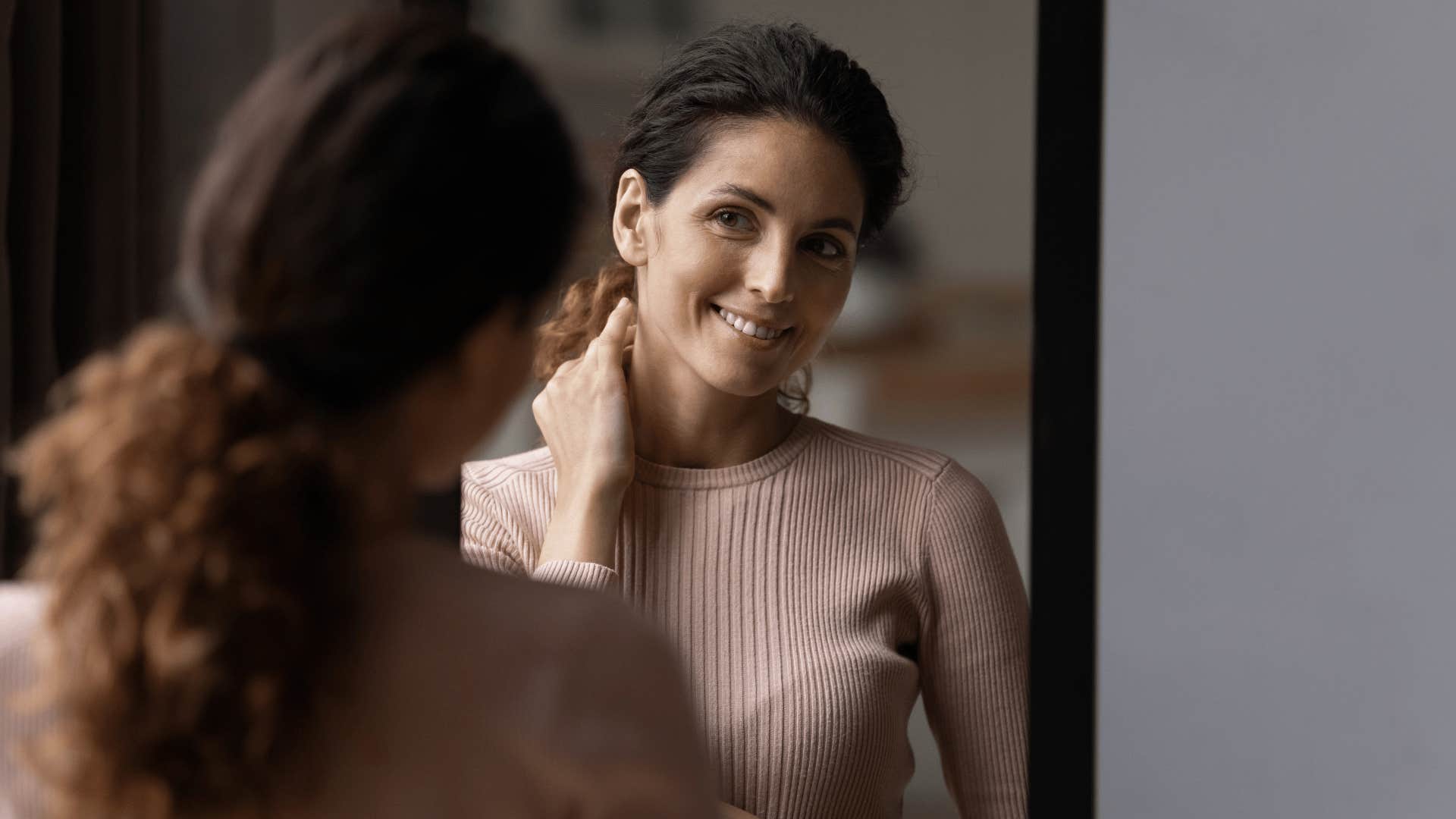 woman smiling at herself in mirror