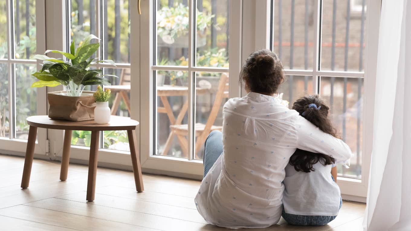 mother and daughter hugging while looking out a window