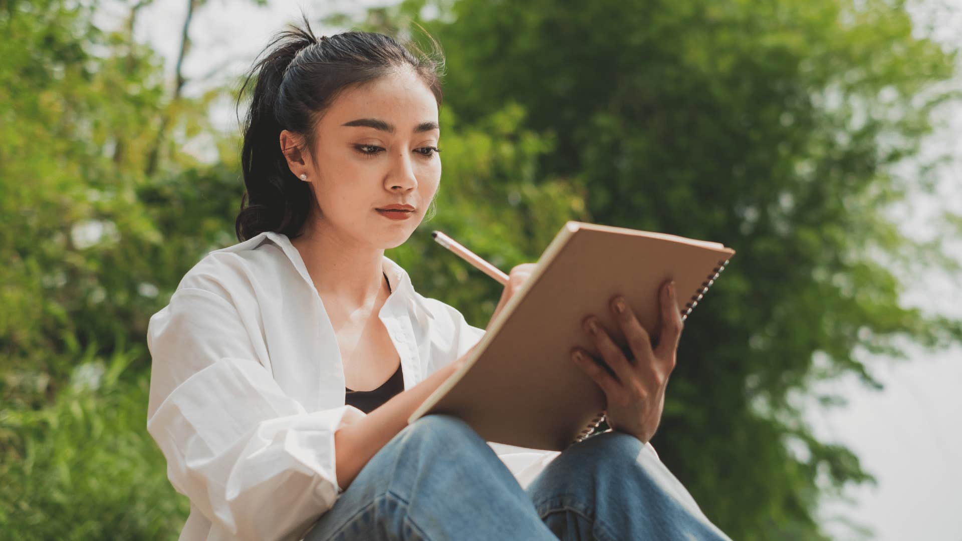 woman sitting outside writing in notebook