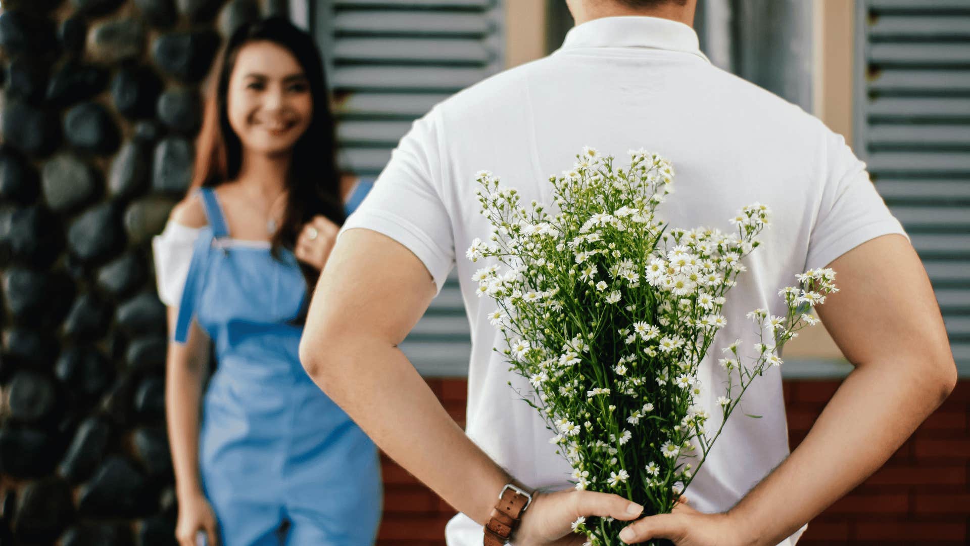 man holding flowers behind back from woman first date