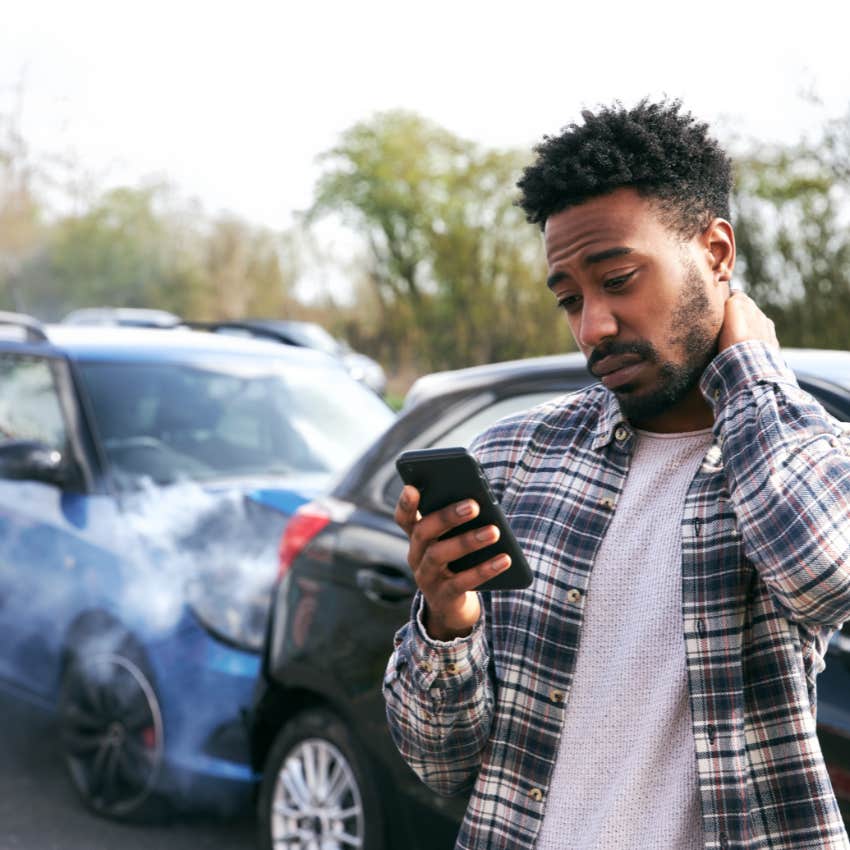 man checking phone after serious car accident