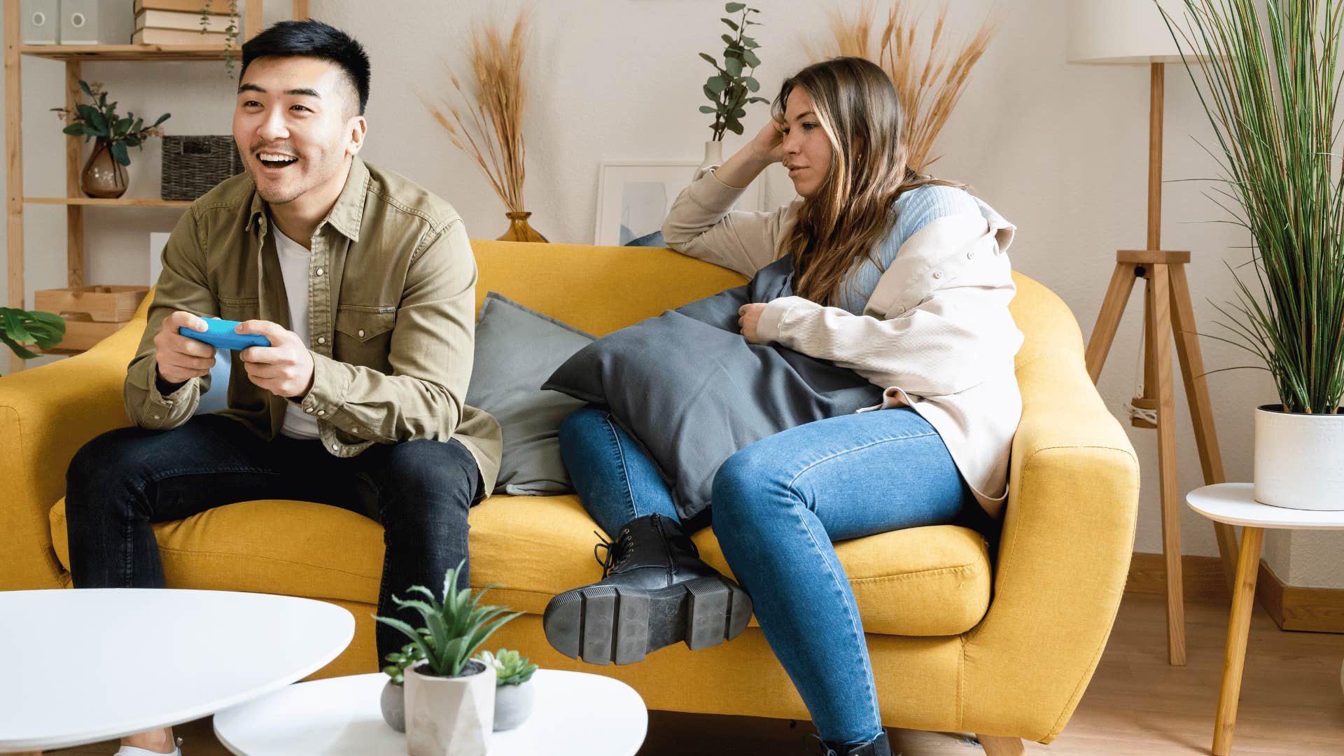 man playing video games on couch next to girlfriend