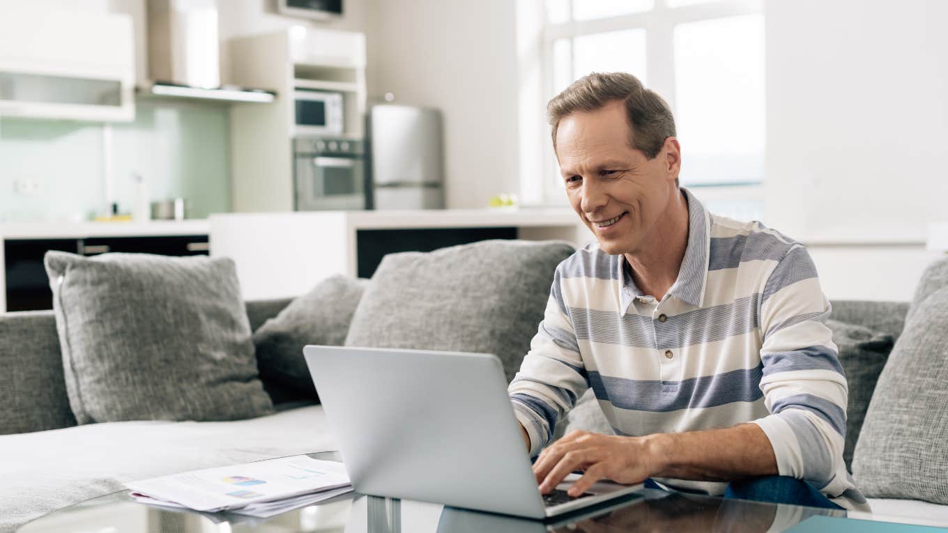 man sitting on his couch at home using his laptop