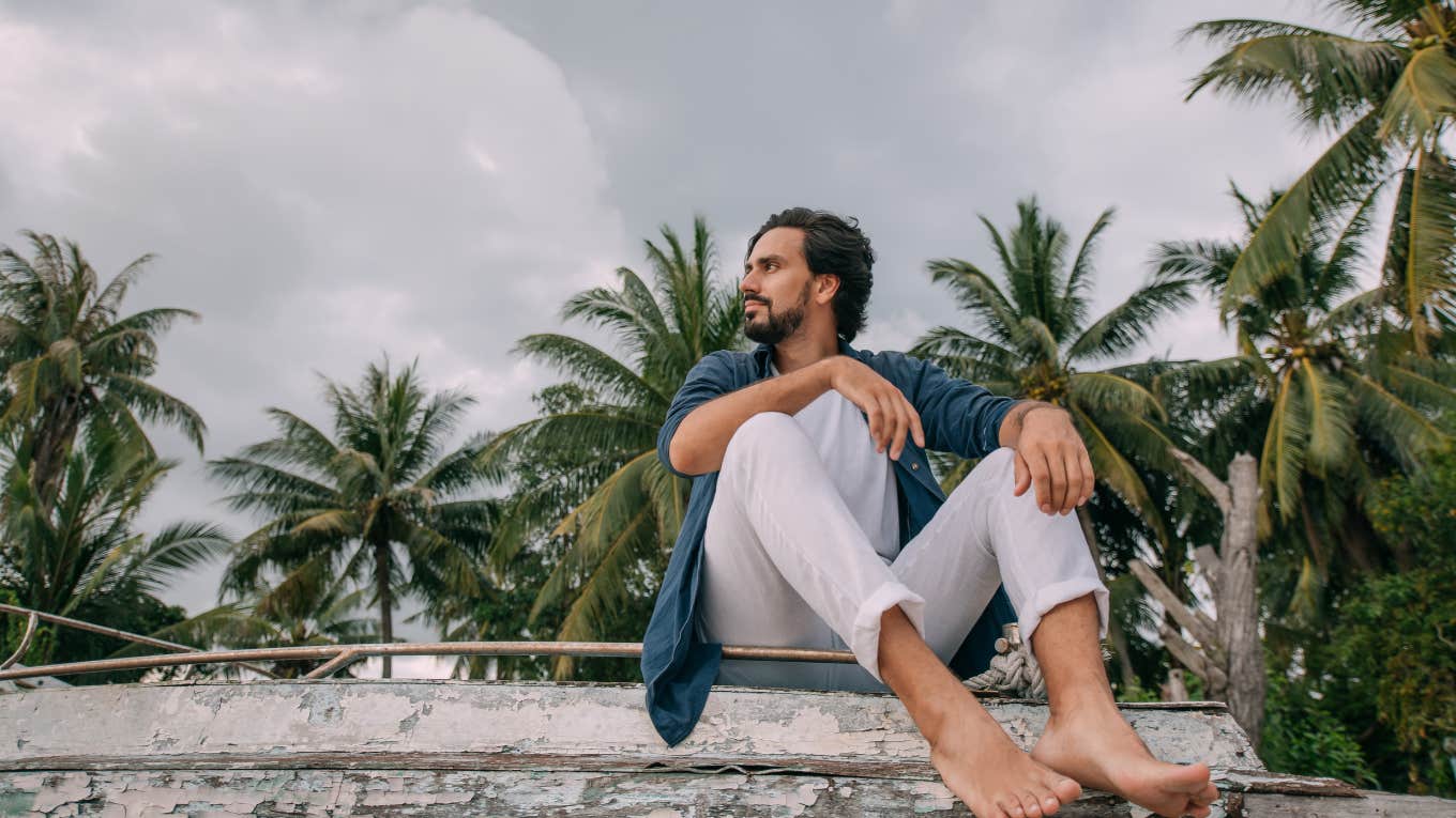 Man looking in the distance thinking with palm trees in the background