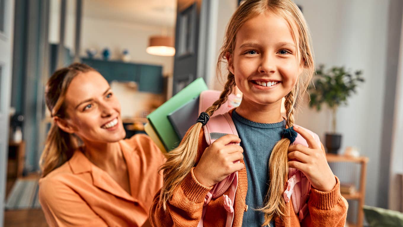 mom putting school supplies in daughter's backpack