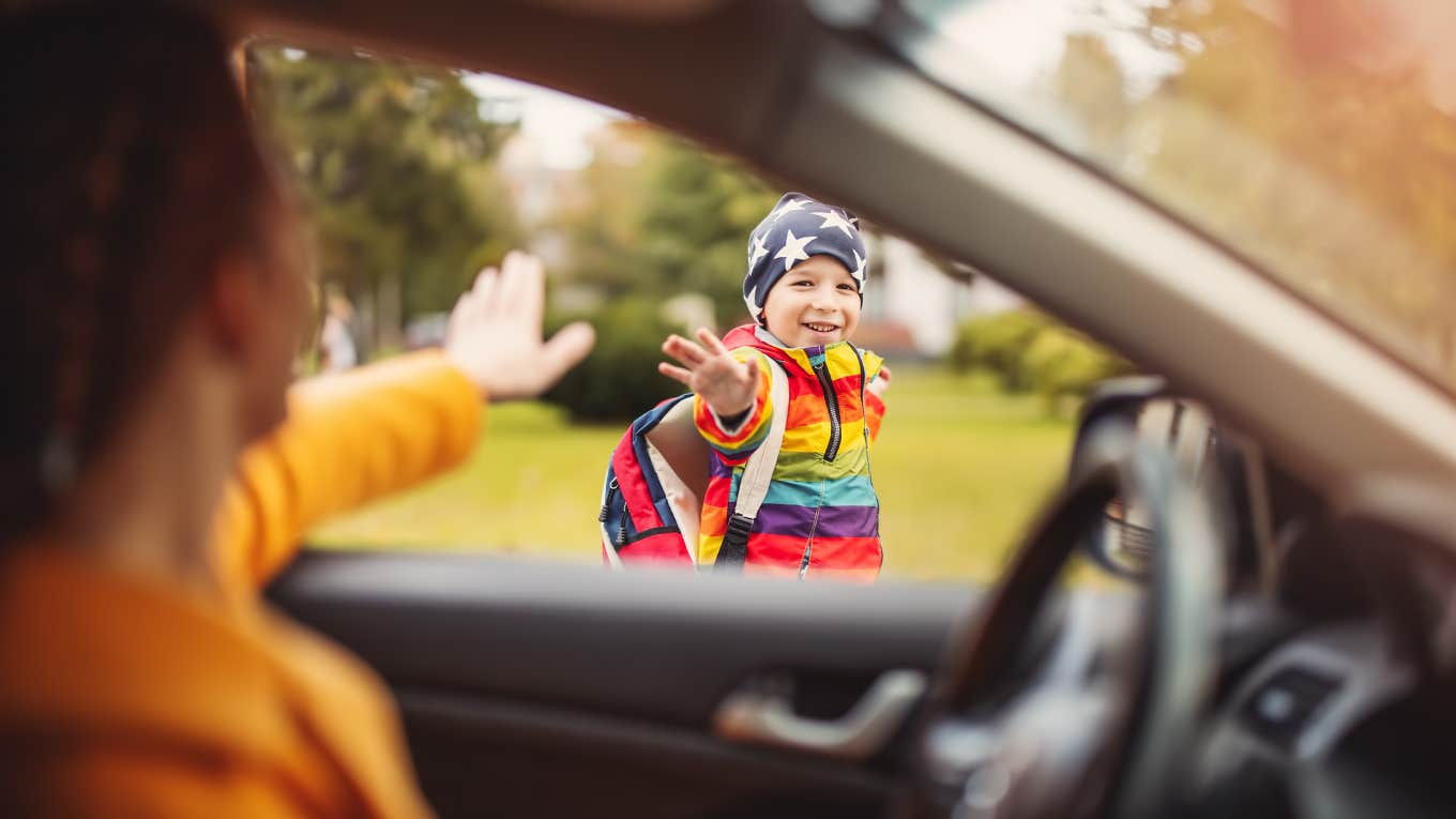 sideview of mom waving at son from driver's seat while dropping him off at school