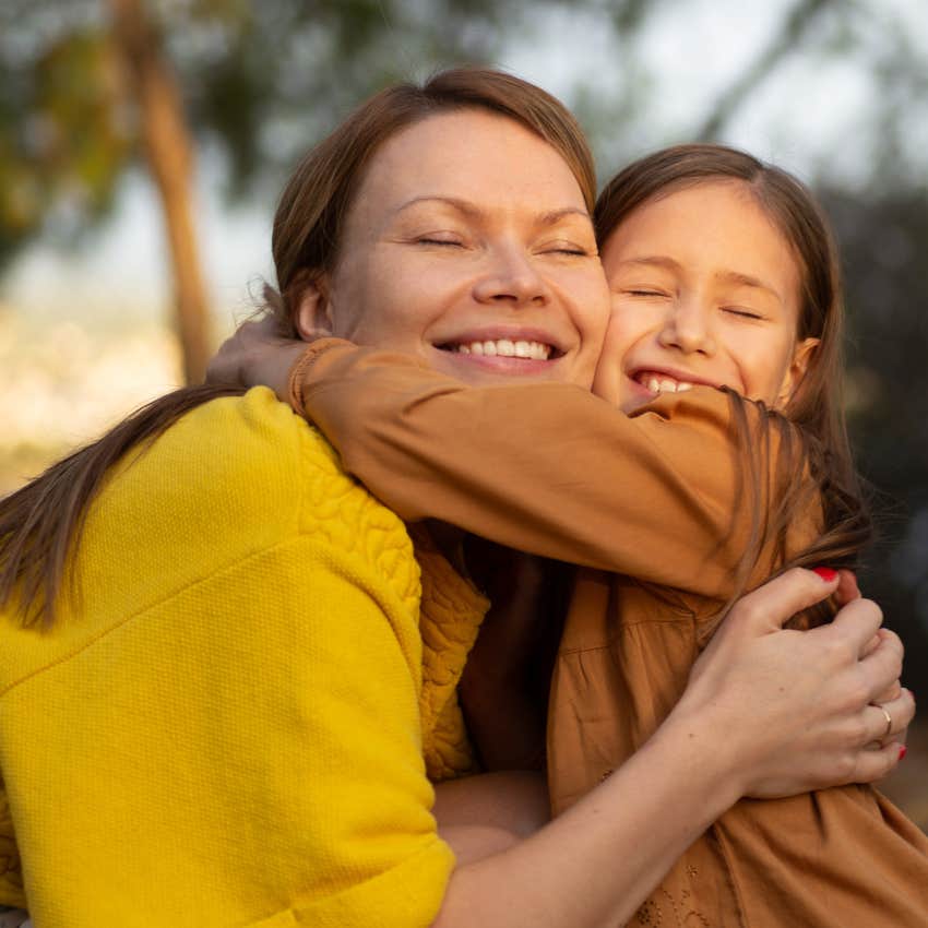 Mom hugging her daughter outside. 