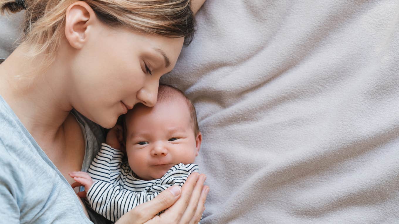 mom laying down on blanket holding baby boy