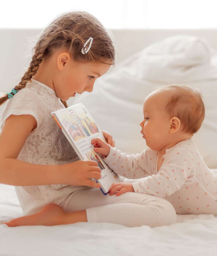 big sister reading to baby sister