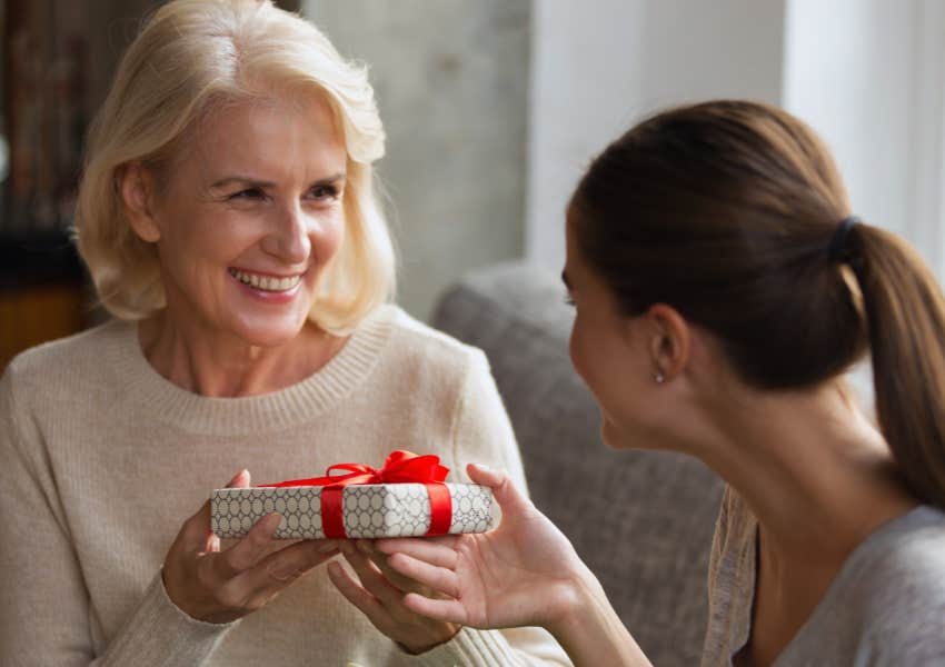 older woman handing wrapped gift to younger woman