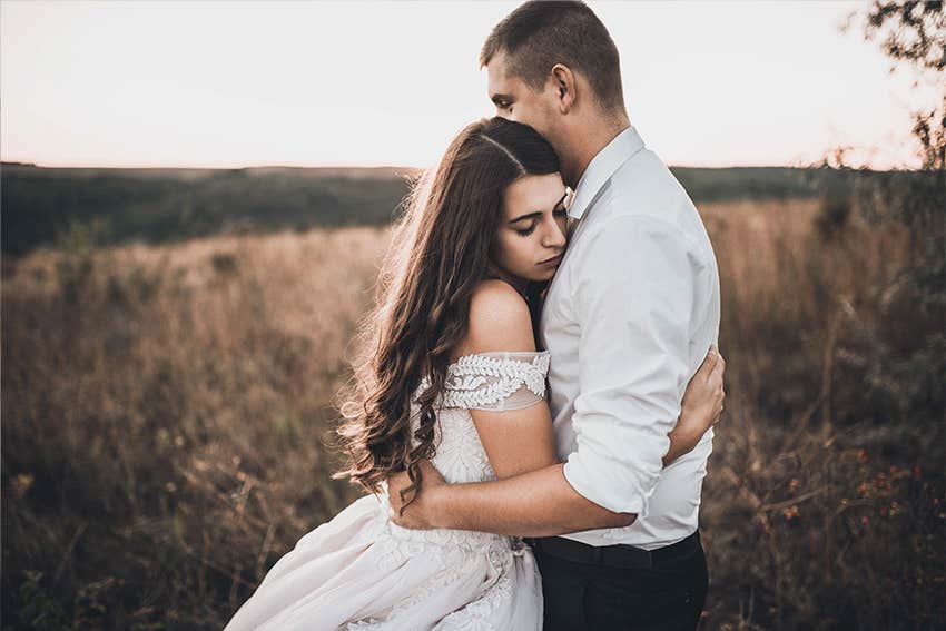 serious couple hugging in a field