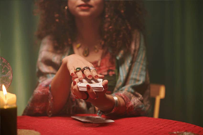 Hands of psychic shuffling tarot cards before spreading on table