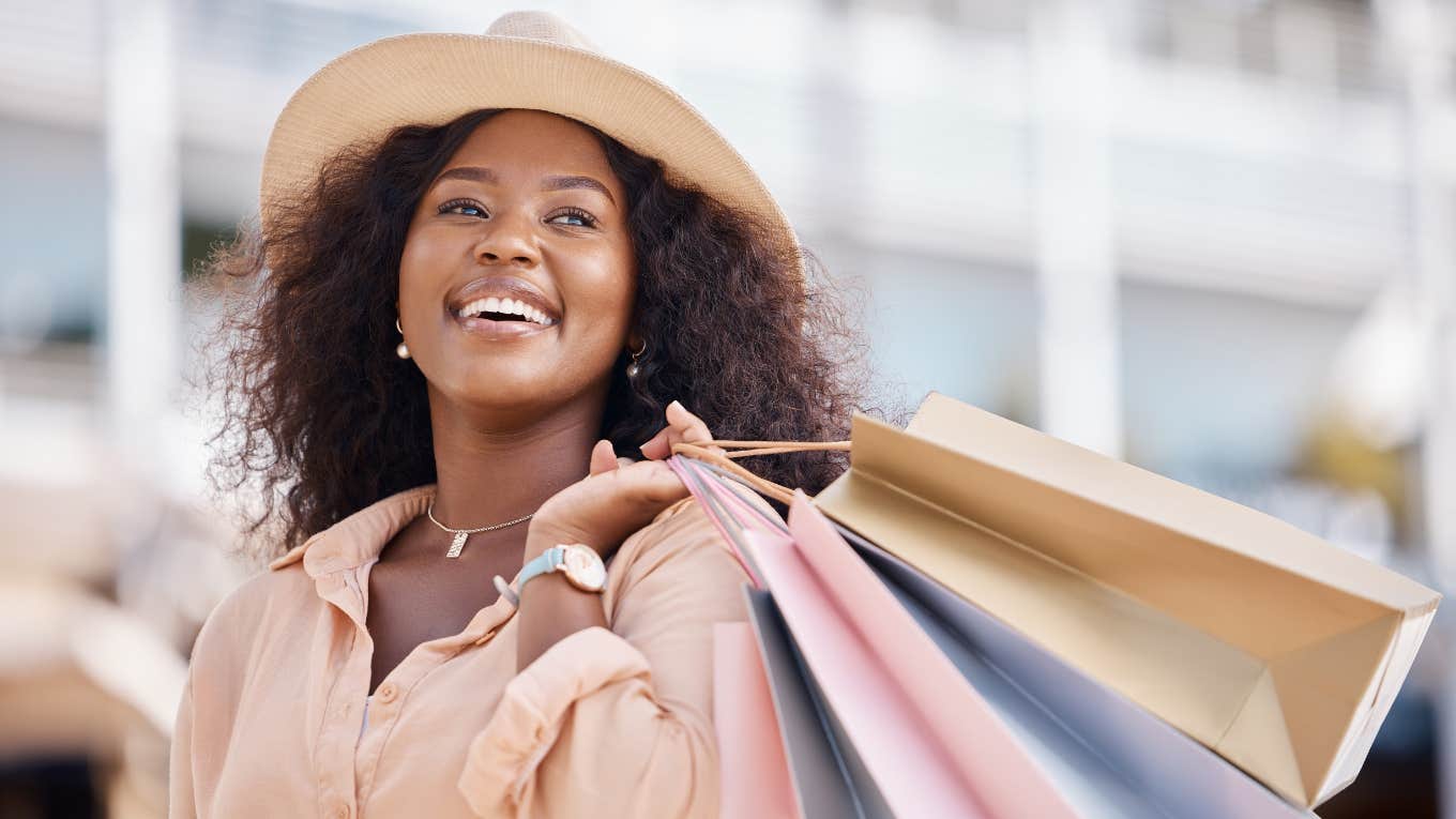 Smiling woman wearing hat and carrying shopping bags