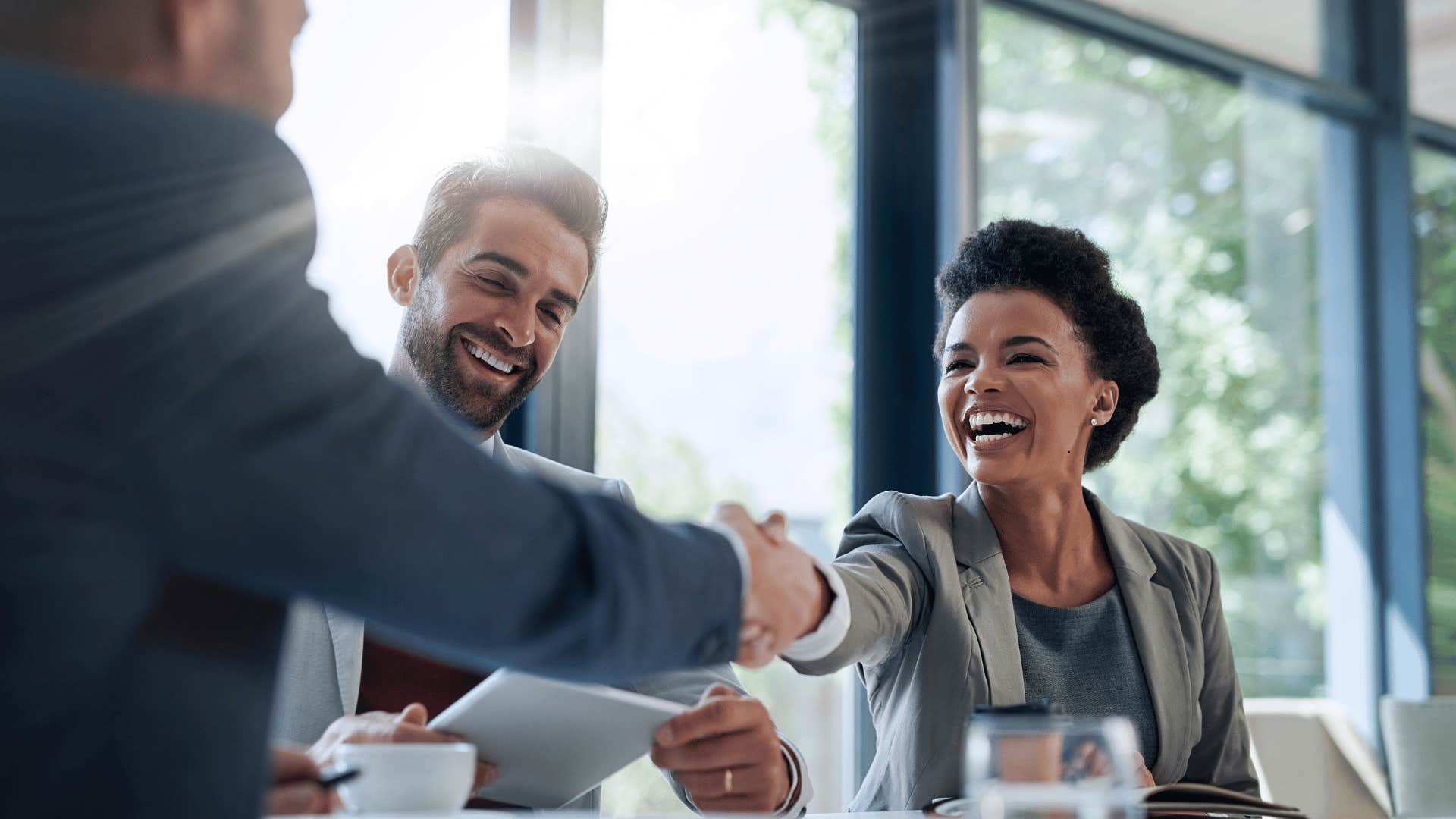 woman shaking mans hand while smiling