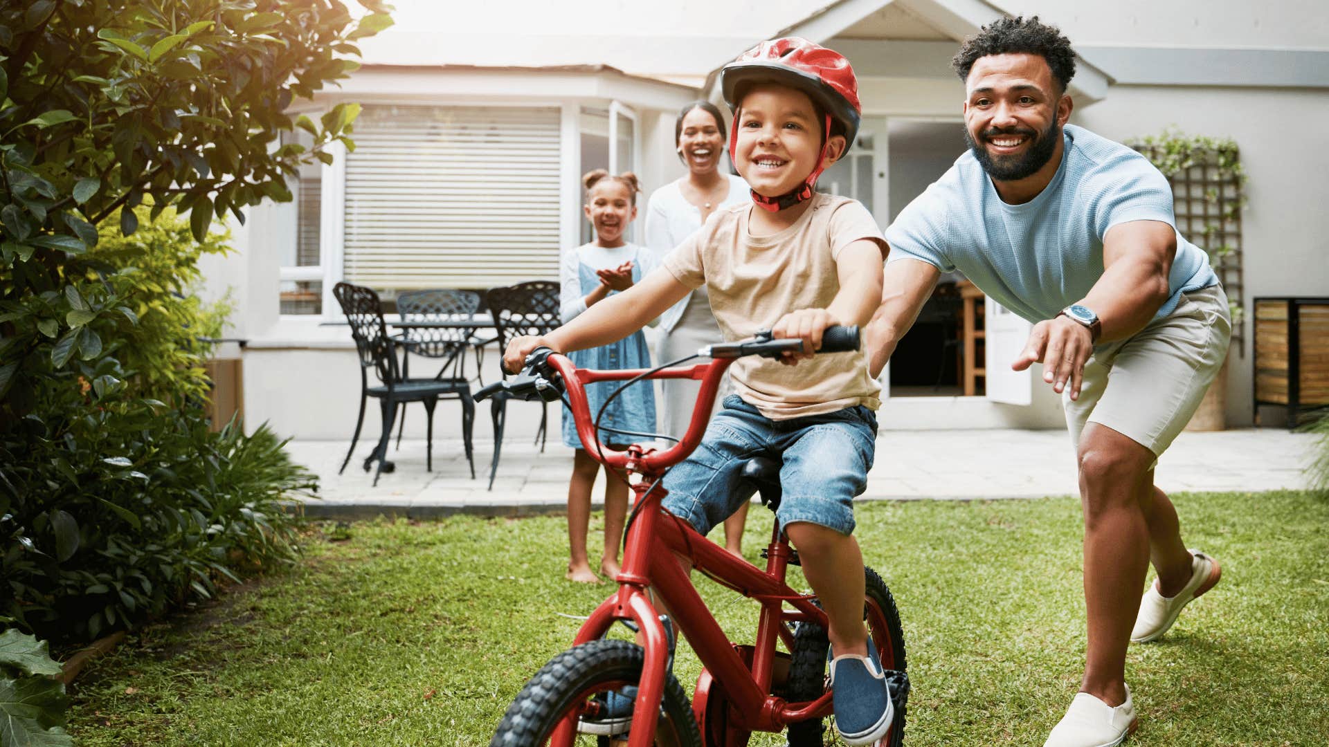 boy riding a bike in backyard with family