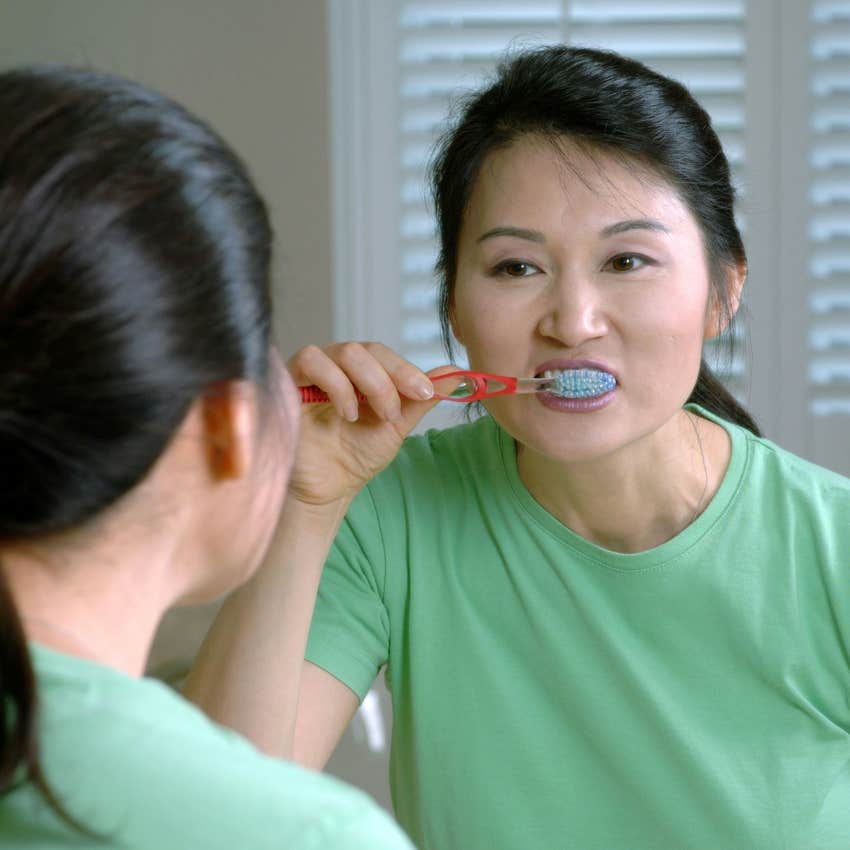 Woman brushing her teeth in the mirror. 