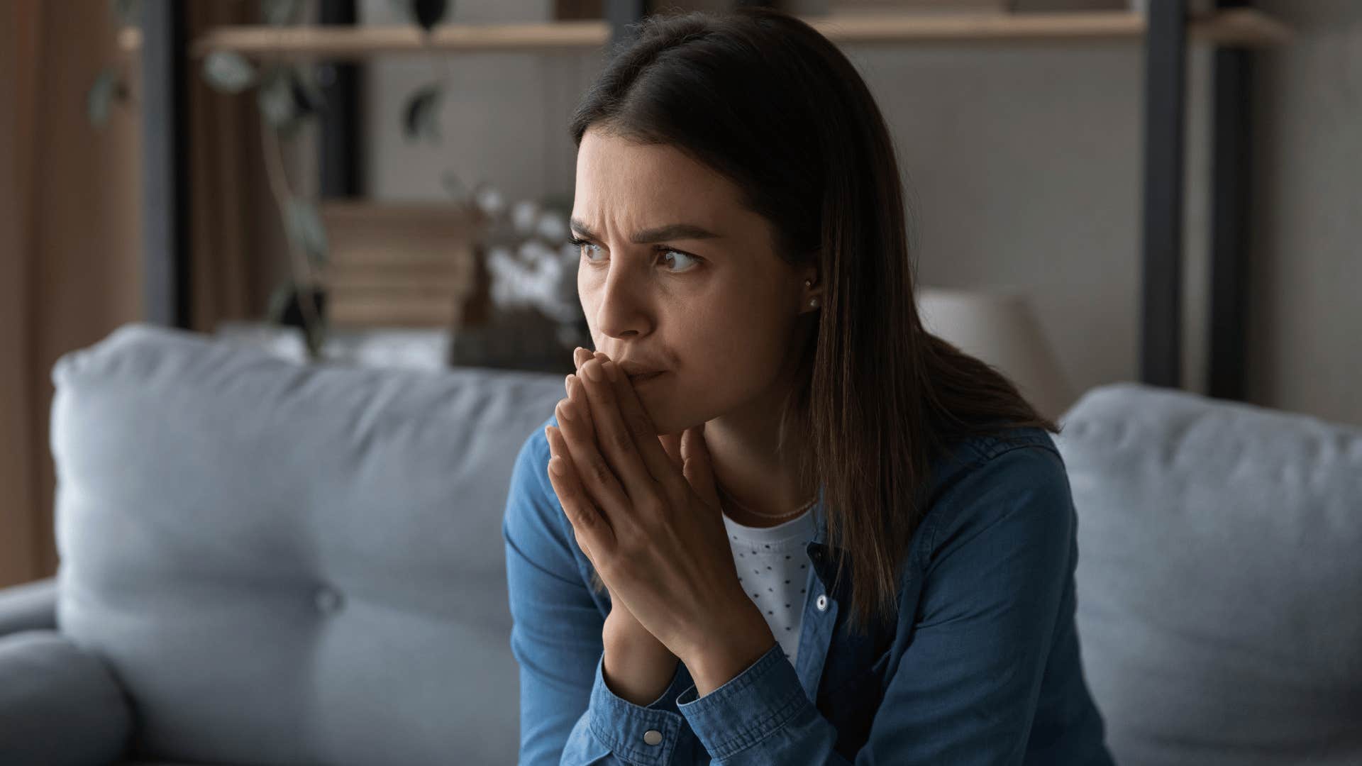 woman looking guilty while sitting on couch