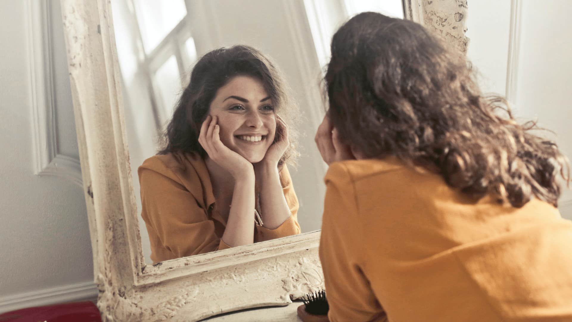 woman smiling while staring at mirror