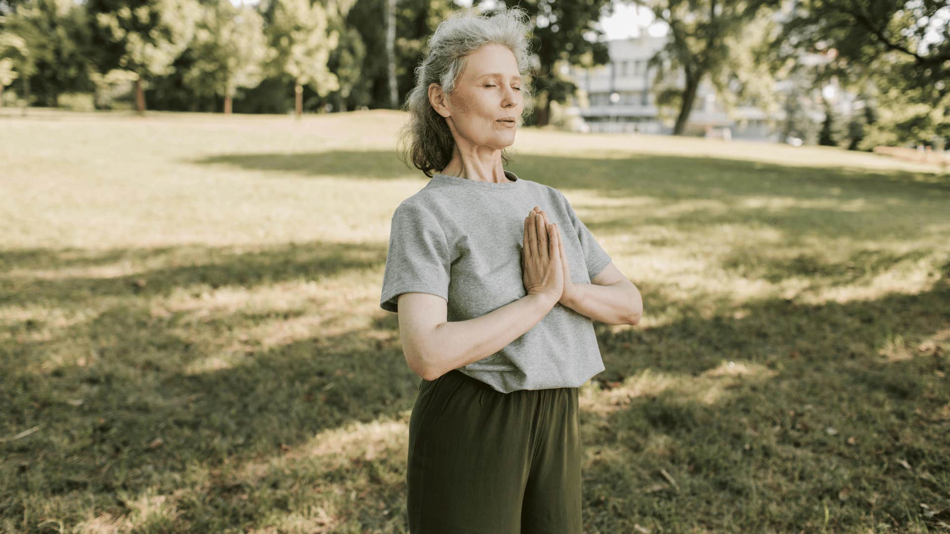 older woman meditating outside 