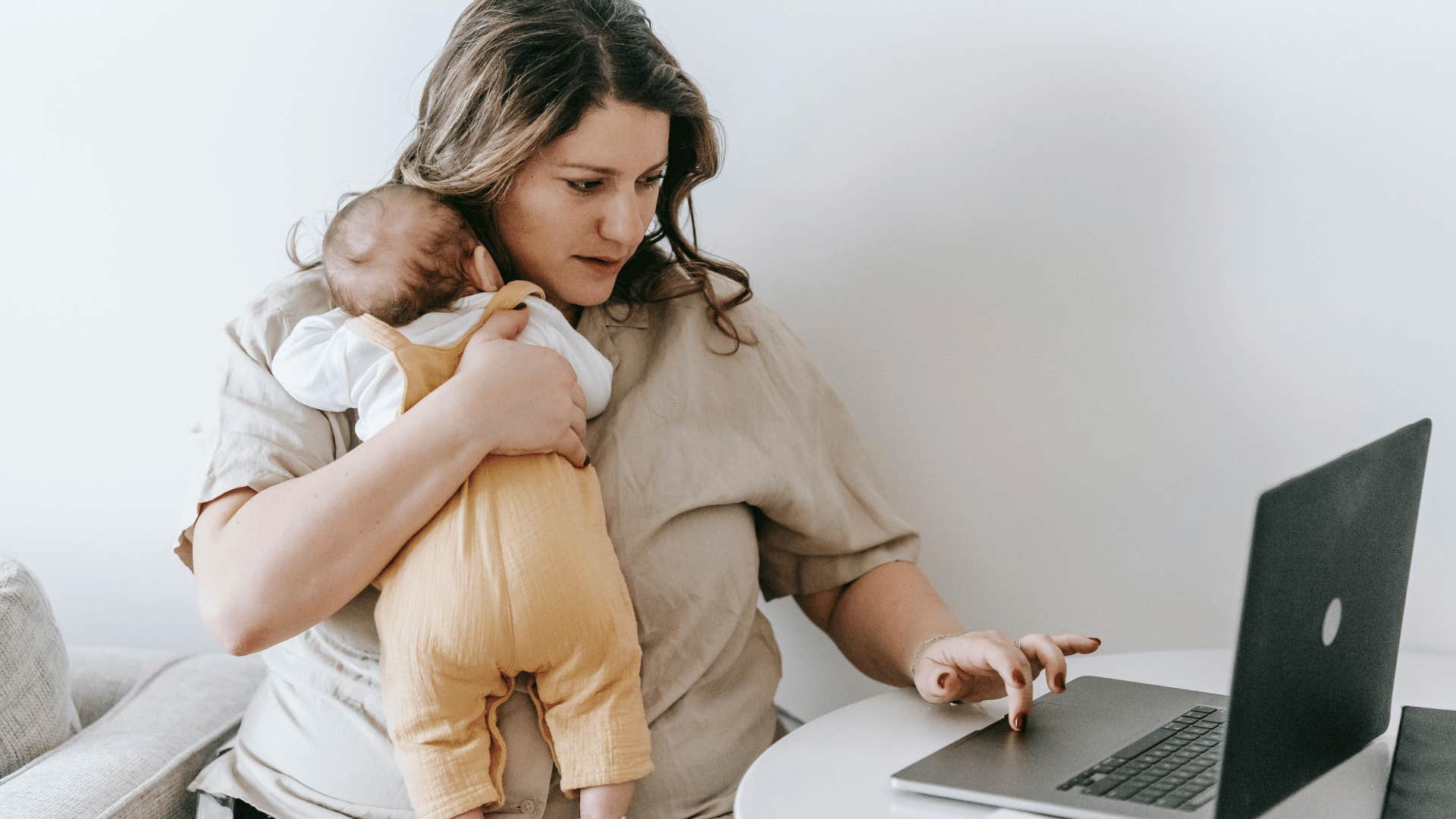 new mom holding baby while working