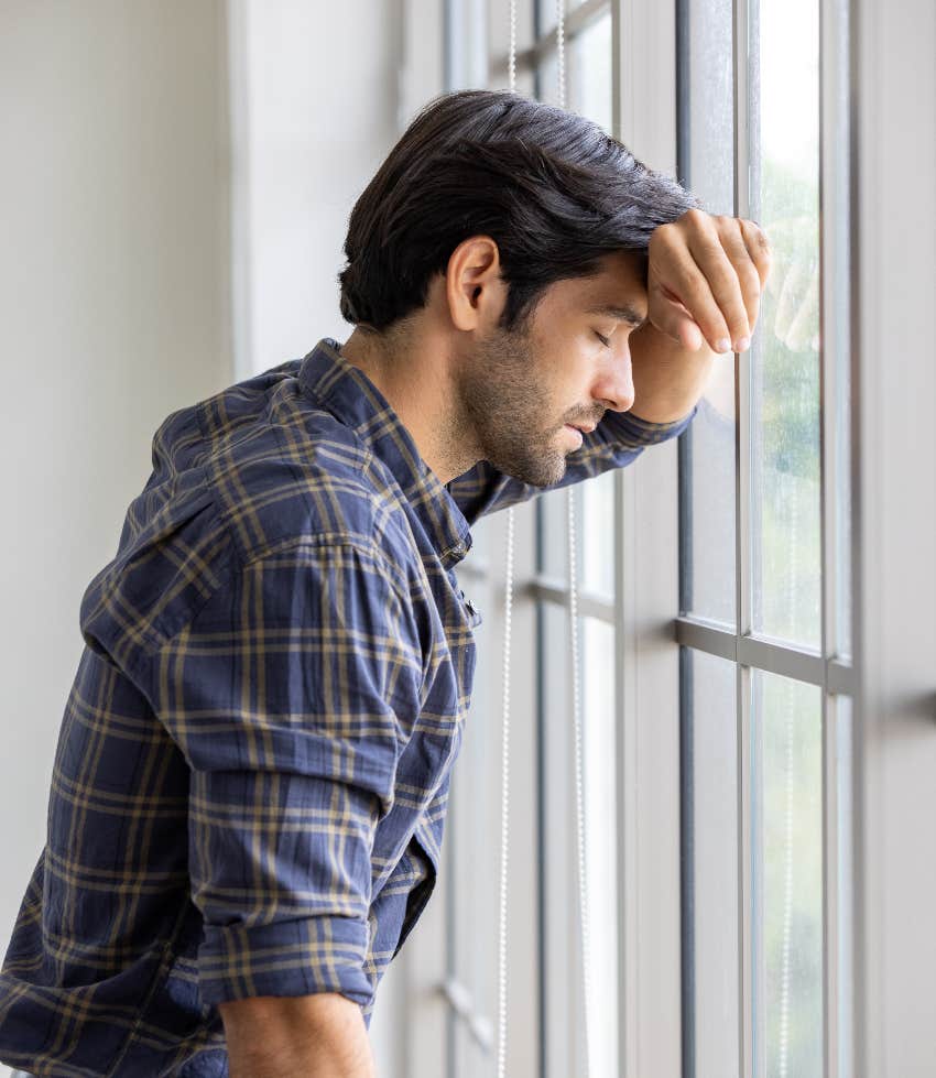 Sad American husband looking out the window at a yard with no kids