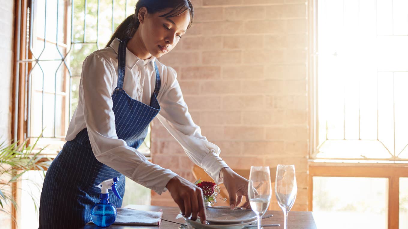 Server cleaning after entitled customers left dishes on table