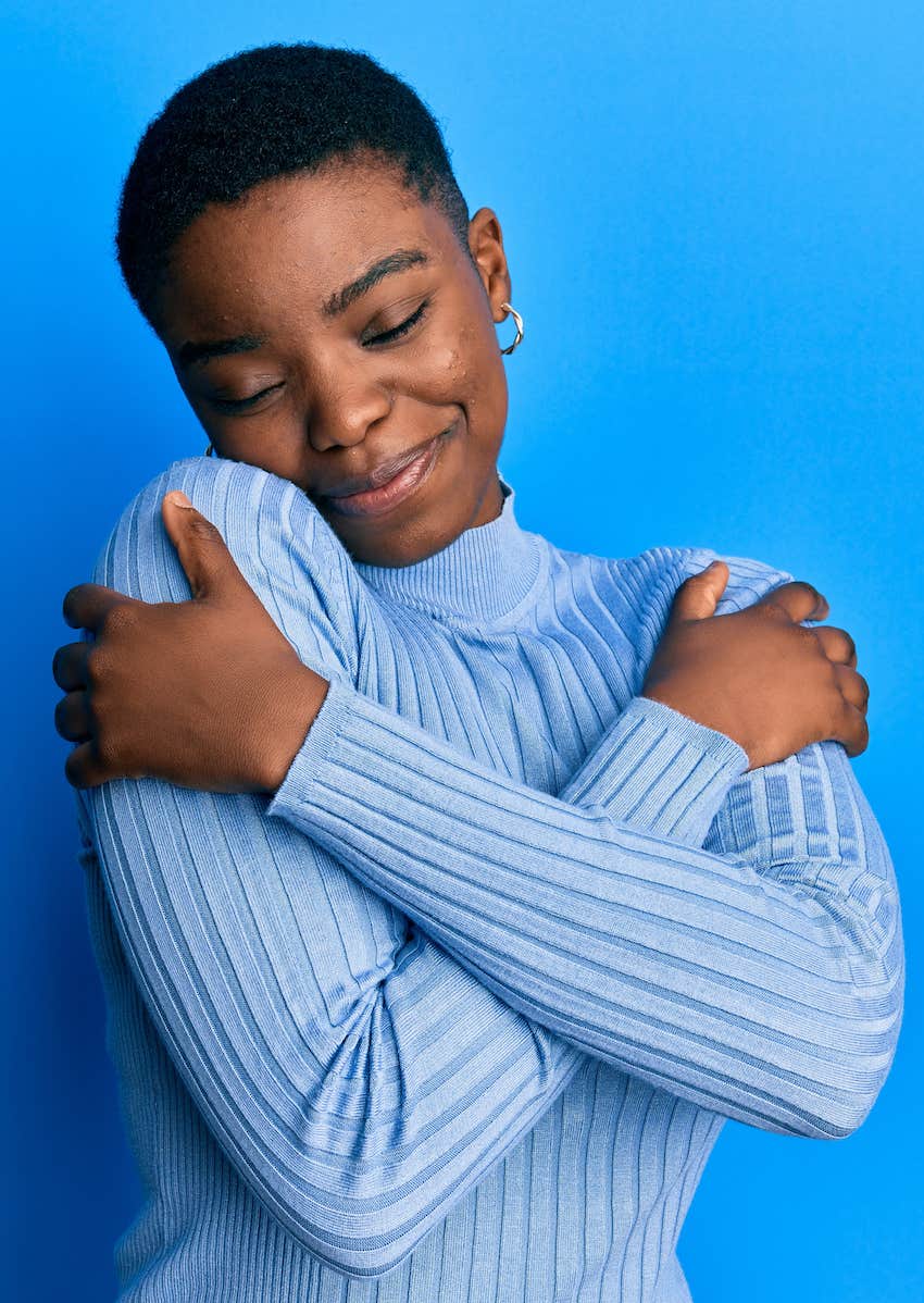 Happy woman hugs herself as a representation of self-love