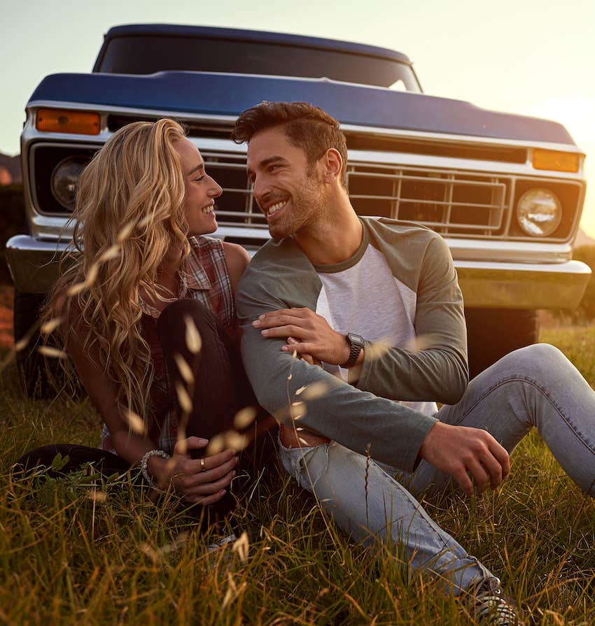 Couple chat in field in front of old truck, he has found the woman of his dreams