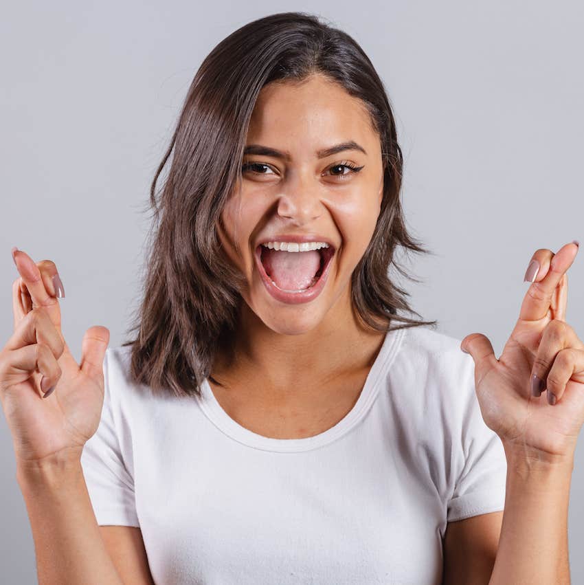 Excited, she crosses her fingers to manifest the guy she wants