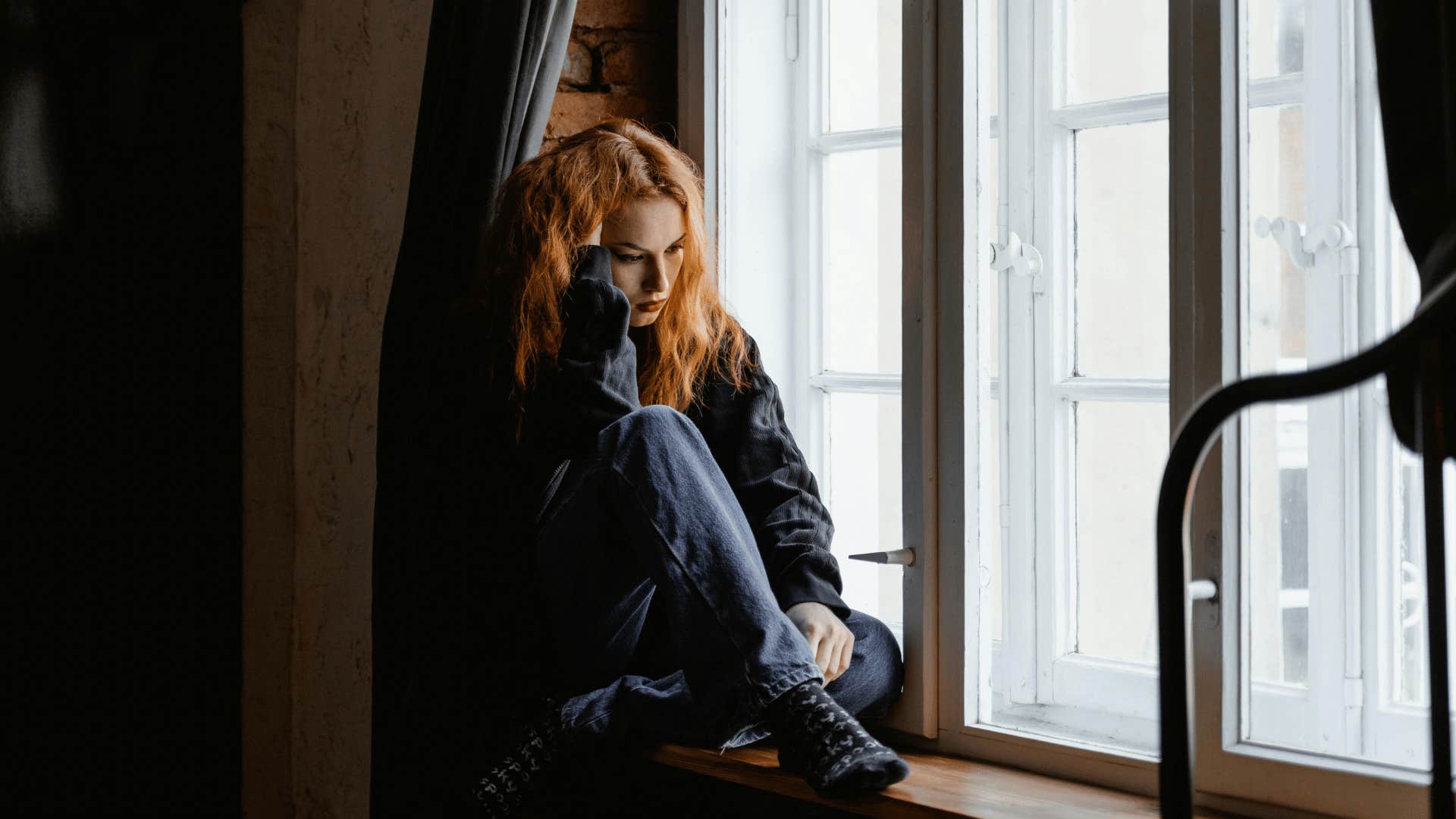 woman looking upset while sitting near window