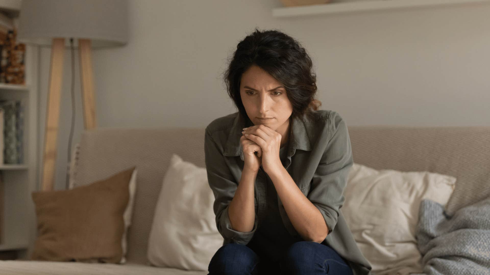 anxious woman sitting on couch thinking