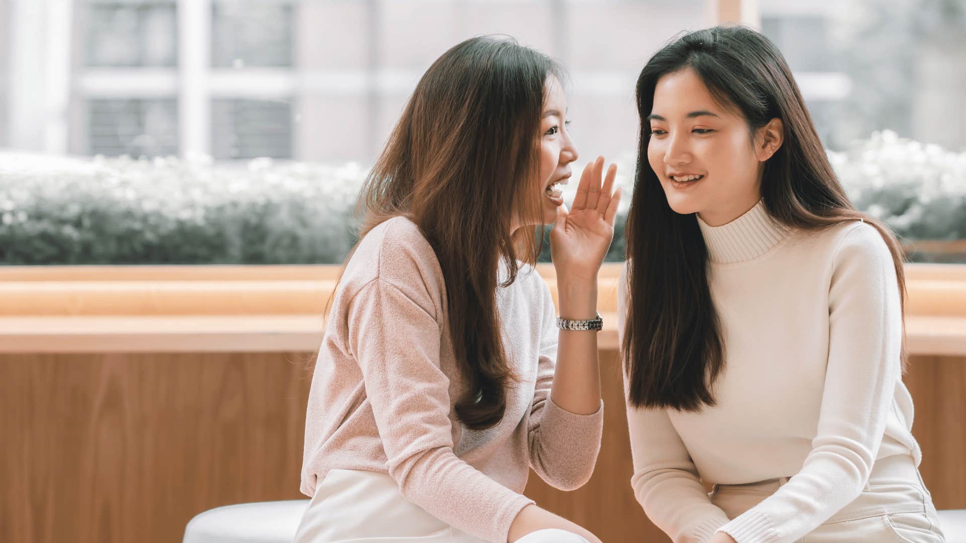 woman whisper in other woman's ear