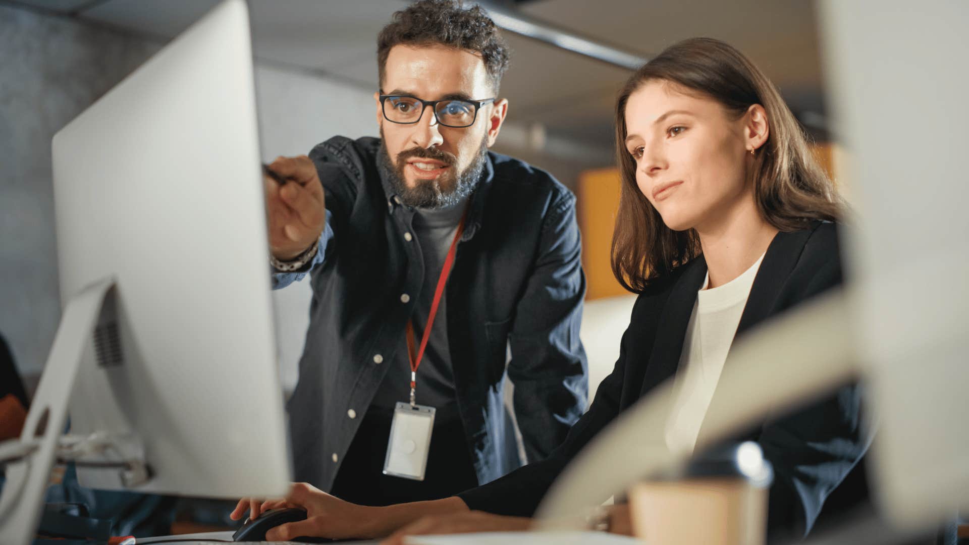 man teaching woman something on computer