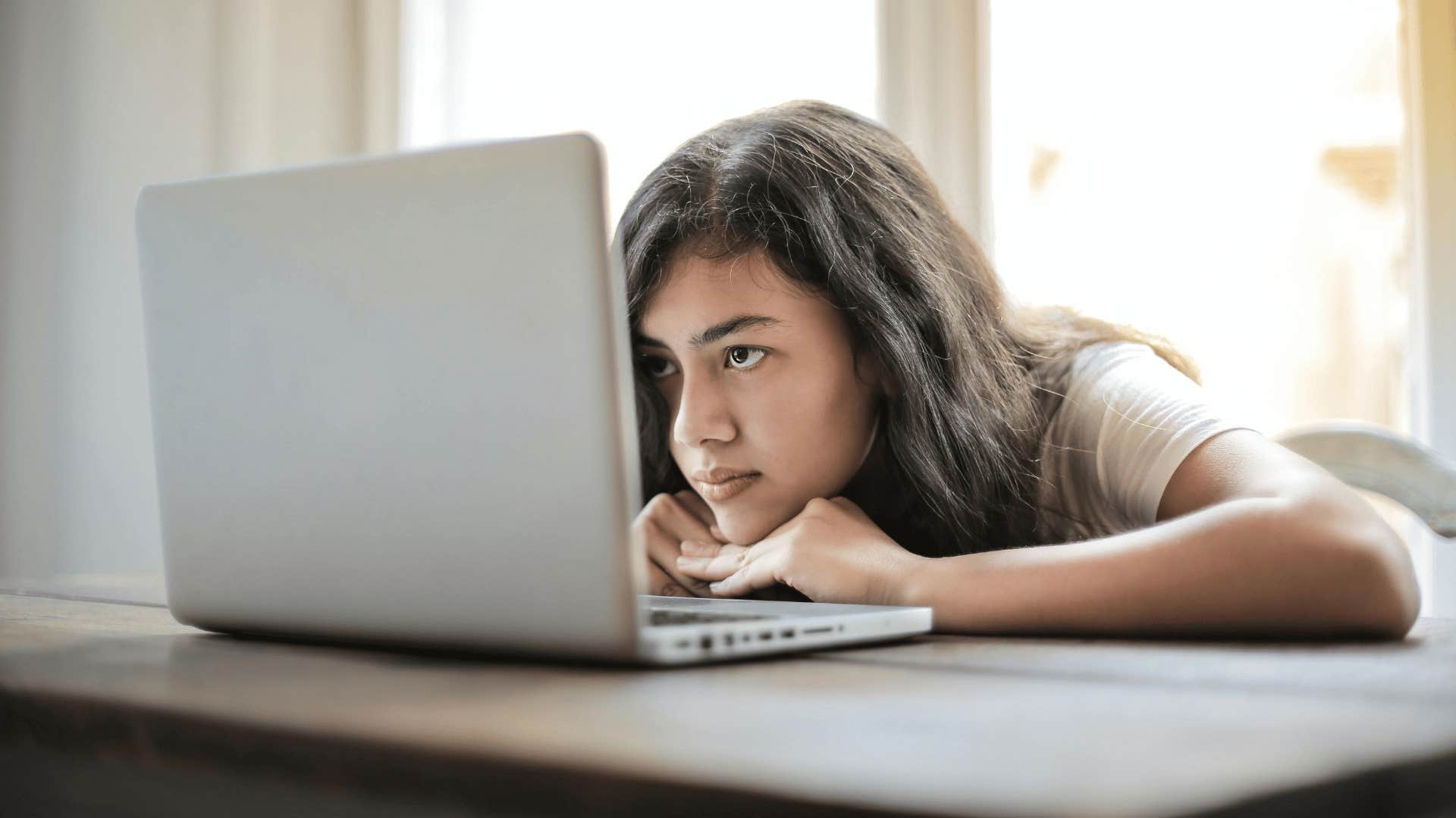 woman bored while staring at laptop