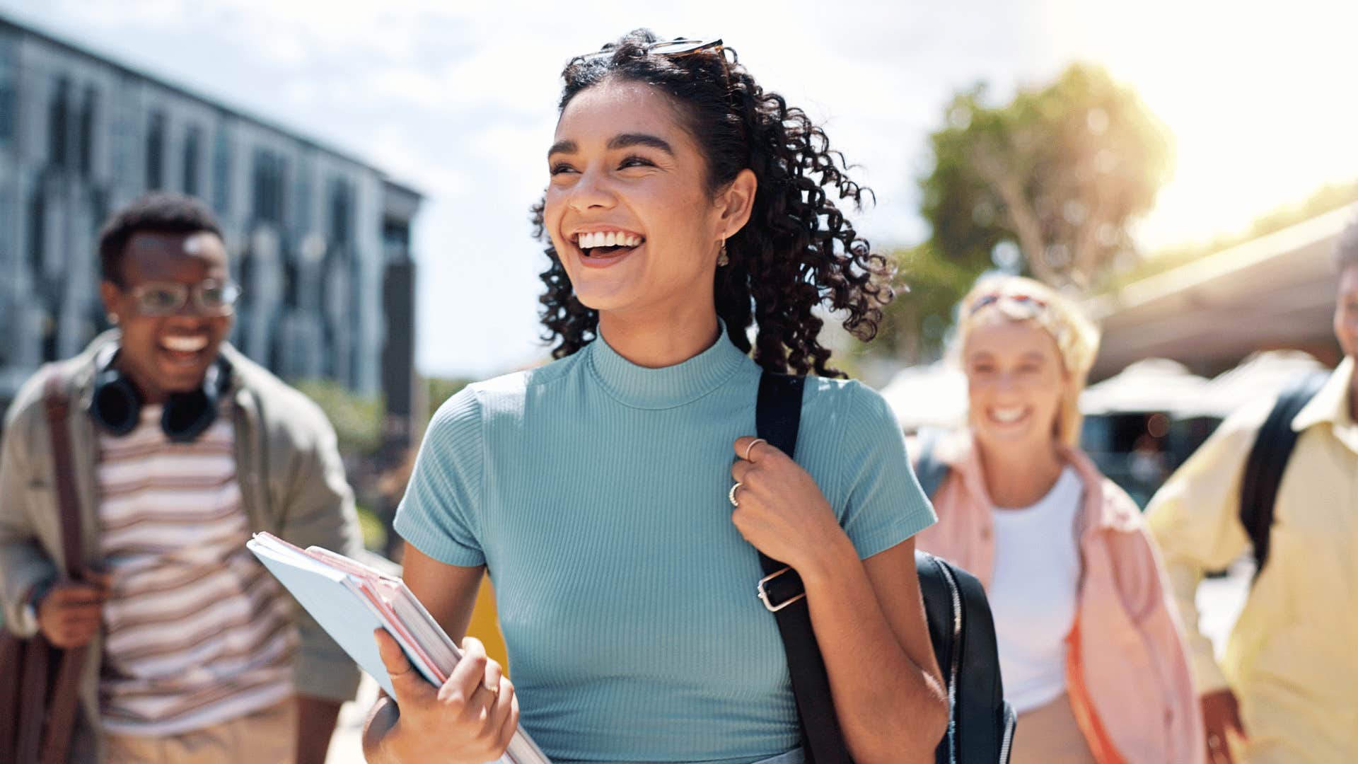 woman walking with notebook in hand smiling 