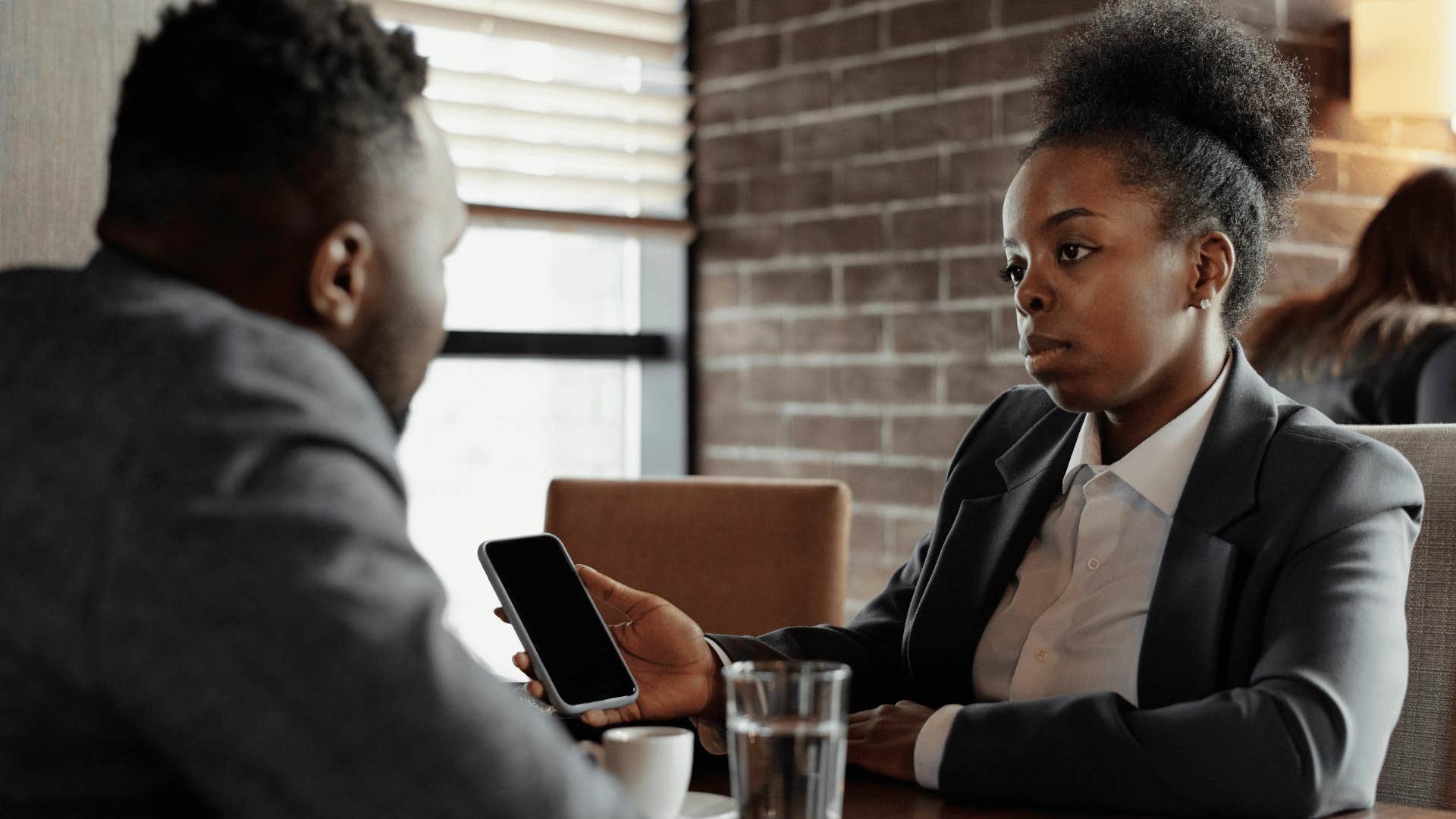 woman sitting with man and showing phone