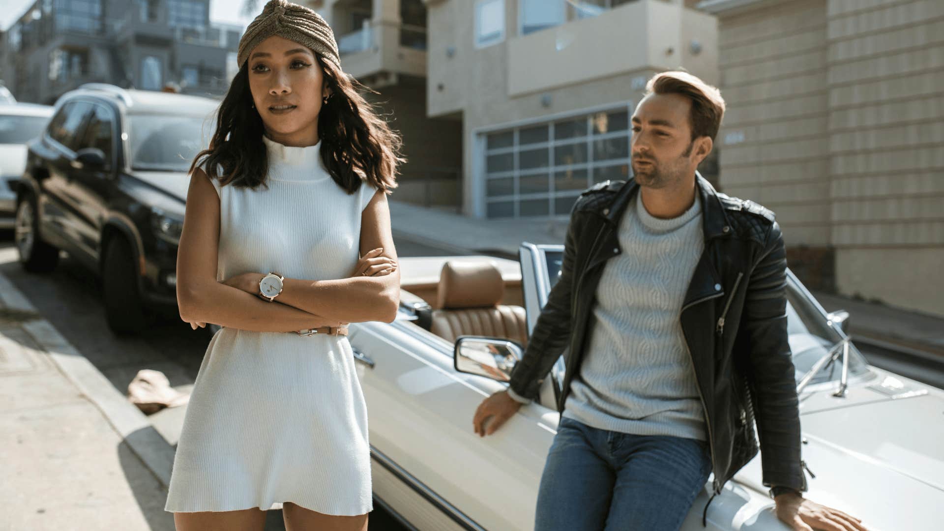 woman walking away from man leaning against car