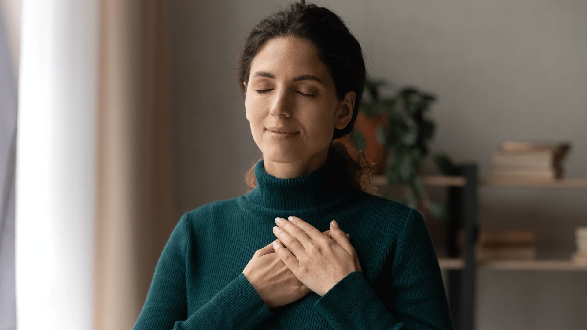 woman closing eyes while putting hand over heart