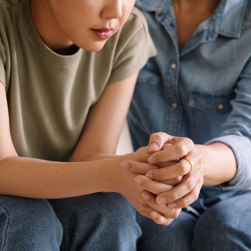 close up of woman comforting young woman and holding her hands