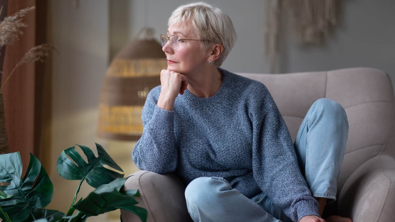 older woman sitting on couch and looking out window