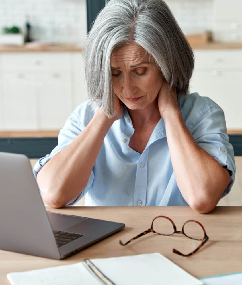 Female employee with hands on neck feeling stressed out