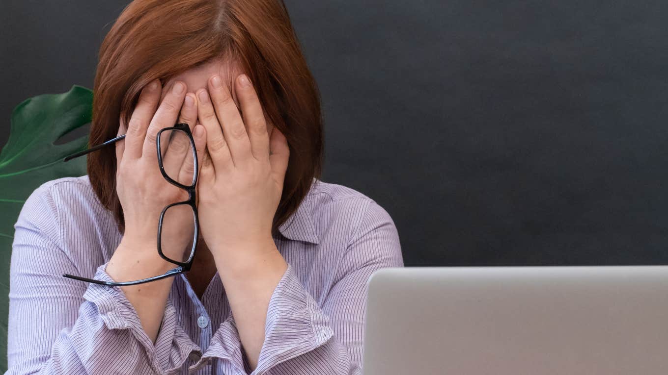 frustrated teacher with head in hands in front of black board