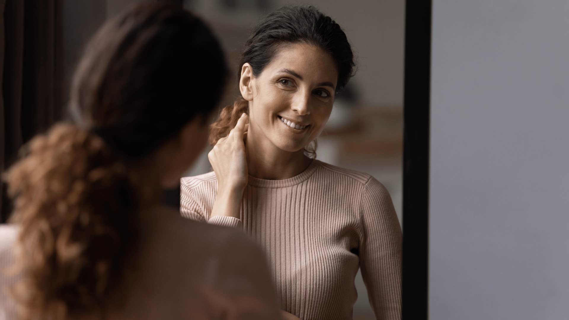 woman smiling at herself in mirror