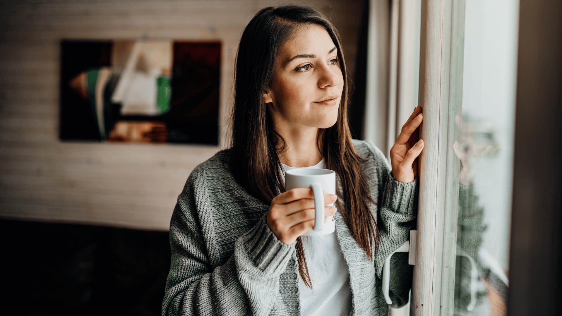 woman staring outside with cup of coffee