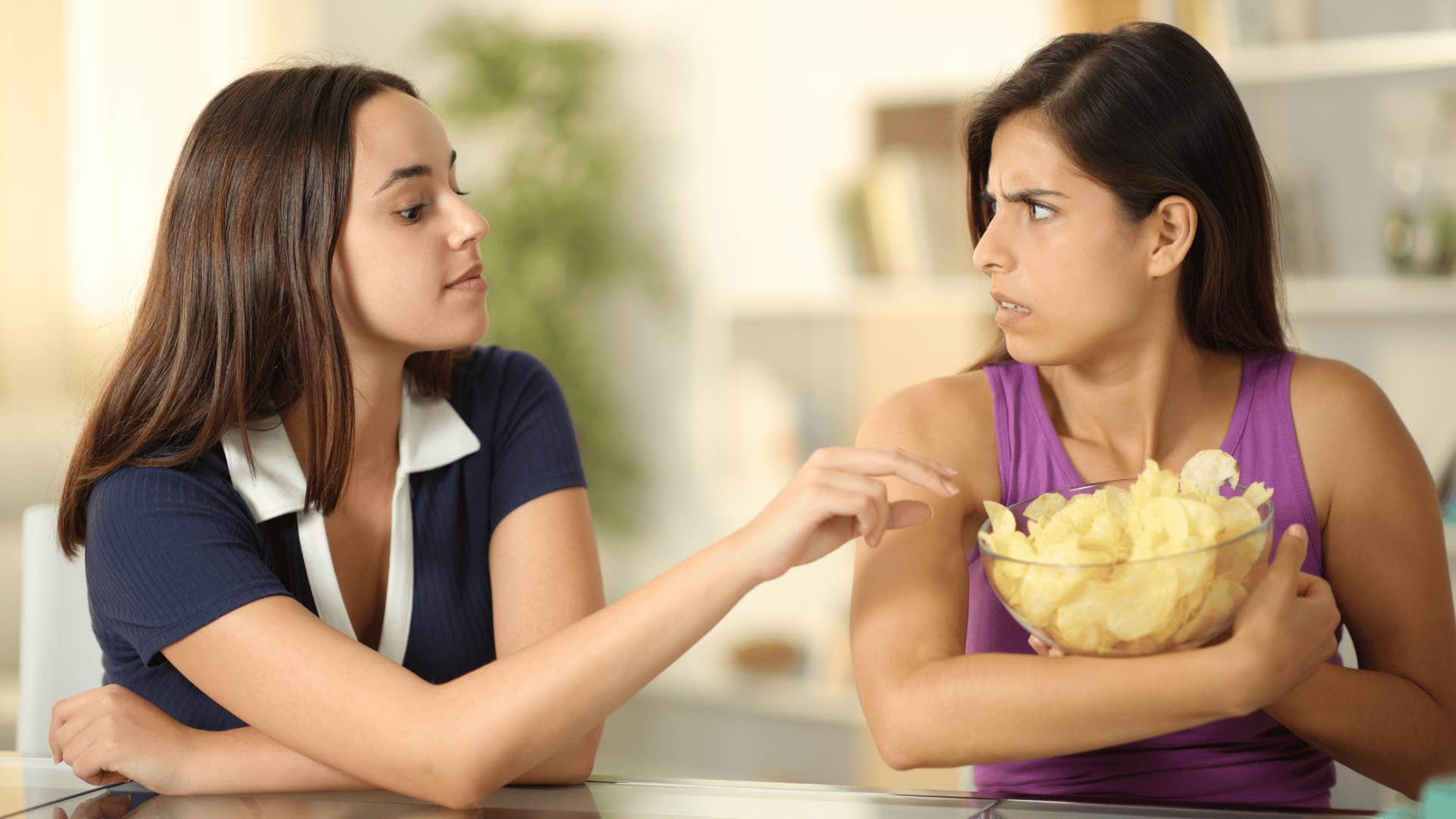 woman refusing to share chips with friend