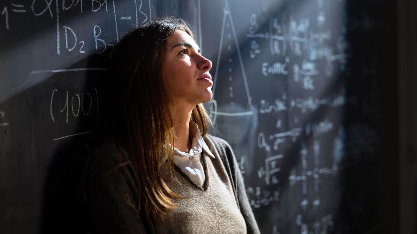 Frustrated teacher leaning against chalkboard